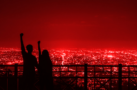 The silhouette of the couple holding hands to express their joy at the Chiang Mai city night view point.の写真素材