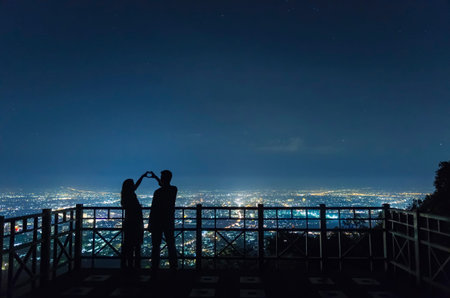 The silhouette of the couple holding hands to express their joy at the Chiang Mai city night view point.の写真素材