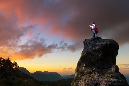 Asian women climbers or backpackers are standing, looking out through the tall treetops on the rocky peaks at sunset, success and winner, leader concept.の写真素材