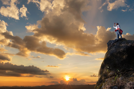 Asian women climbers or backpackers are standing, looking out through the tall treetops on the rocky peaks at sunset, success and winner, leader concept.の写真素材