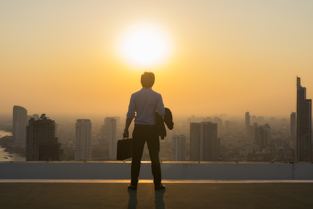 Vision concept, Young business man on the roof of the building and look through to find out goals and success with ambition and commitment to success in the job.の写真素材