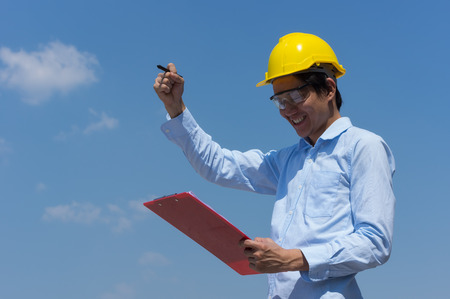 Engineer smile wearing yellow helmet and checklist.の写真素材