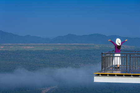 Hipster woman standing on Wooden bridge view point and Tung Bua Tong Mexican sunflower field in Mae Moh Coal Mine, Lampang Province, Thailand.の写真素材