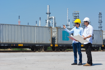 Engineers wear white safety helmets and workers are consulted with the oil refineries background.の写真素材