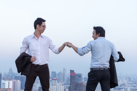 Business teamwork, businessman standing at the top of the building,  showing fist bump for success teamwork corporate and looking through the scenery of the city.の写真素材
