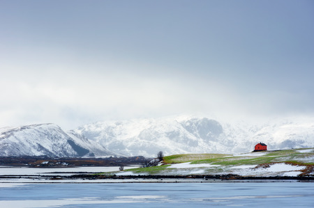The  beautiful distinctive red house on the green lawn, view of scenic Lofoten Islands archipelago winter scenery, Beautiful mountain landscape in winter Norway, Scandinavia.の写真素材