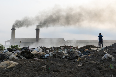 Photographers are taking photos of industrial waste and air pollution with black smoke from the chimney.の写真素材