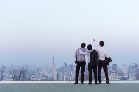 Business teamwork concept, businessman standing at the top of the building and looking through the cityscape.の写真素材