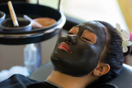 Woman with black Mud Facial Mask. Beauty and Wellness, Beautiful Young Woman with natural Facial Mask on her Face in spa health and relaxing concept.の写真素材
