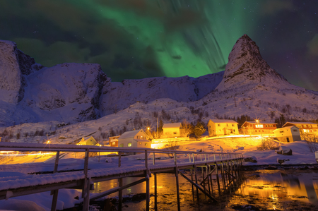 Beautiful Snow-covered wooden bridge and mountain view of scenic Lofoten Islands archipelago winter scenery, with Northern Lights or Aurora Borealis, Beautiful landscape in winter Norway, Scandinavia.の写真素材