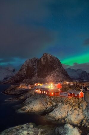 Beautiful view of night scenic fishing hut in the Hamnoy and Lilandstinden mountain peak Lofoten Islands archipelago winter scenery, Beautiful mountain landscape in winter Reine Norway, Scandinavia.の写真素材