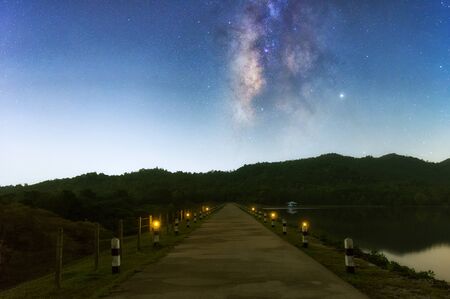 Road into the mountains in Huai King Reservoir at night, the starry sky is the gateway to the dream, a beautiful Milky Way galaxy with stars and space dust exposed to long speeds.の写真素材