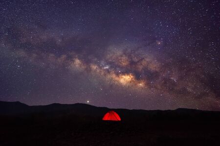Red tent in reservoir under Milky way galaxy with stars and space dust in the universe, long speed exposure with noise. Baan Sop pat, Mae Moh Lampang Thailand.の写真素材