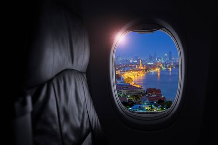 Airplane interior with window view of Wat Arun, or the Temple of Dawn is a striking structure, landmark of Thailand, Concept of travel and air transportation.の写真素材