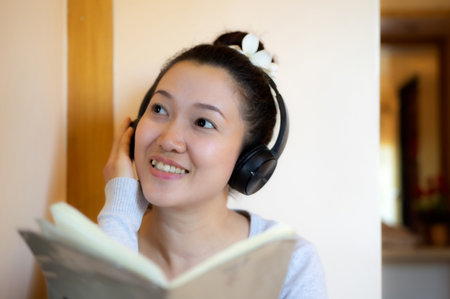 Asian teenage girl reading and listening to music happily.の写真素材