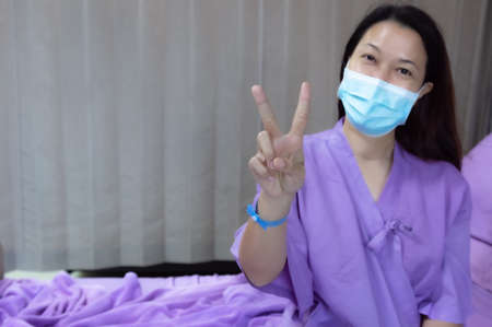 Asian female patient smiling and showing encouragement. Patients feel happy and comfortable when they are treated by hospitalization in the hospital room. Medical health care conceptの写真素材