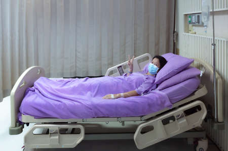 Asian female patient smiling and showing encouragement. Patients feel happy and comfortable when they are treated by hospitalization in the hospital room. Medical health care conceptの写真素材