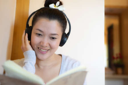 Asian teenage girl reading and listening to music happily.の写真素材