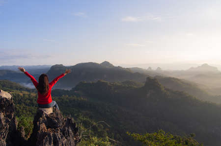A young women is hike on a clear day. she glad that have successfully climbed the mountain, and admiring nature, and morning mist and the beautiful sun rays. Ban Jabo, Mae Hong Son, Thailandの写真素材
