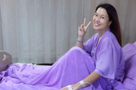Asian female patient smiling and showing encouragement. Patients feel happy and comfortable when they are treated by hospitalization in the hospital room. Medical health care conceptの写真素材