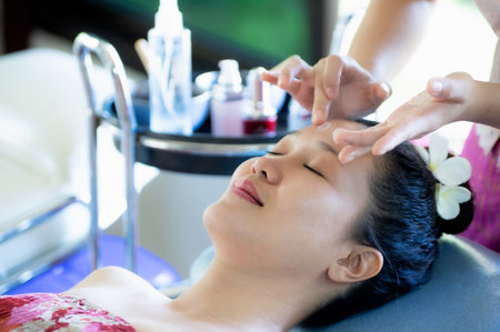 A beautiful Asian woman lays down to the staff to clean her skin and apply moisturizer, skin care around her face.の写真素材