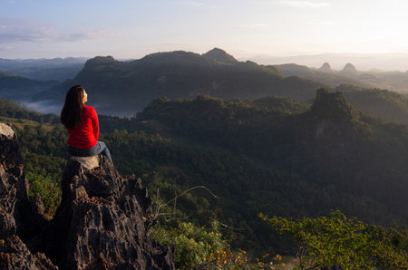 A young women is hike on a clear day. She admiring nature, and morning mist and the beautiful sun rays, Mountain Climbing, Rock Climbing. Ban Jabo, Mae Hong Son, Thailandの写真素材