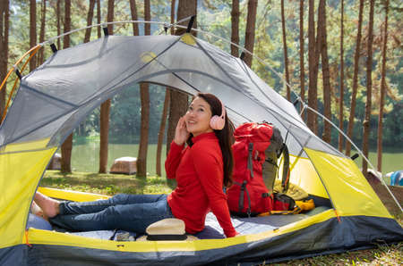 Woman Enjoy listening to music from headphones. She sat in a yellow tent. beside Lake, Pang Oung, Mae Hong Son, Thailandの写真素材
