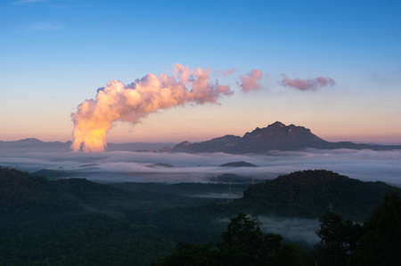 Beautiful sea of fog in the mountains, high voltage pole and steam from the coal power plant in the morning sunrise . Mae moh, Lampang, Thailand. Energy and environment concept .の写真素材