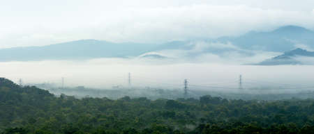 Panorama aerial view transmission tower in green forest and beautiful morning smooth fog. Energy and environment concept. High voltage power poles. Mae Moh, Lampang.の写真素材