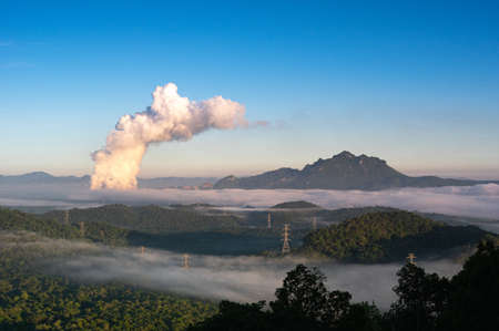 Beautiful sea of fog in the mountains, high voltage pole and steam from the coal power plant in the morning sunrise . Mae moh, Lampang, Thailand. Energy and environment concept .の写真素材