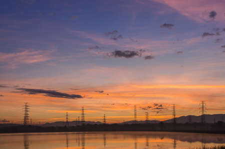 Lined high voltage poles and reflections in the beautiful morning water and lake view, Mae Moh, Lampang, Thailandの写真素材