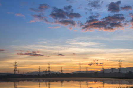 Lined high voltage poles and reflections in the beautiful morning water and lake view, Mae Moh, Lampang, Thailandの写真素材