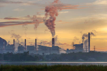 Coal power plant and steam from the flue in the beautiful morning among the mountains and lakes. Mae Moh, Lampang, Thailand. Lines a row high voltage pole.の写真素材