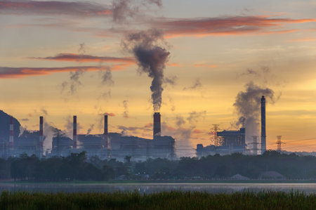 Coal power plant and steam from the flue in the beautiful morning among the mountains and lakes. Mae Moh, Lampang, Thailand. Lines a row high voltage pole.の写真素材
