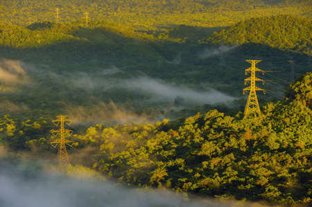 Aerial view Transmission tower in green forest and beautiful morning smooth fog. Energy and environment concept. High voltage power poles. Pang Puay, Mae Moh, Lampang, Thailand.の写真素材