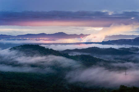 Aerial view mist after the rain on the mountain high voltage pole and steam from a coal power plant at sunset, Pang Puey, Mae Moh, Lampang, Thailand. Energy and environment concept. Long exposure.の写真素材