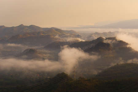 Aerial view Transmission tower in green forest and beautiful morning smooth fog. Energy and environment concept. High voltage power poles. Pang Puay, Mae Moh, Lampang, Thailand.の写真素材