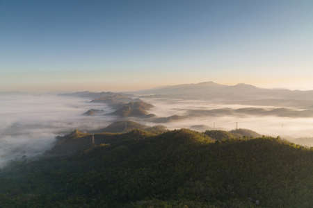 Fog in the morning forest with green mountains and high voltage pole. Pang Puai, Mae Moh, Lampang, Thailand.の写真素材