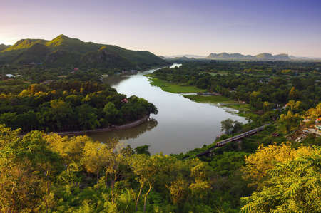 The beautiful landscape in the morning of the Kwai Noi River curve and the mountains at the Golden Chedi Viewpoint Wat Tham Khao Pun, Kanchanaburi.の写真素材