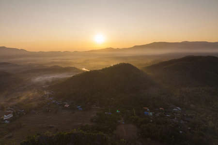Fog in the morning forest with green mountains and high voltage pole. Pang Puai, Mae Moh, Lampang, Thailand.の写真素材