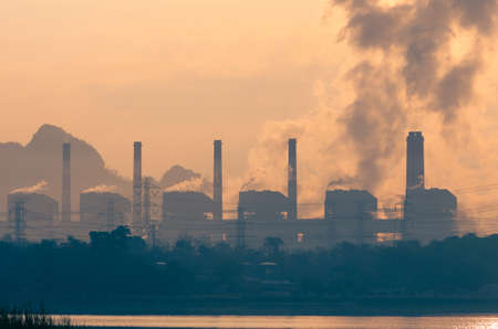 Coal power plant and steam from the flue in the beautiful morning among the mountains and lakes. Mae Moh, Lampang, Thailand. Lines a row high voltage pole.の写真素材