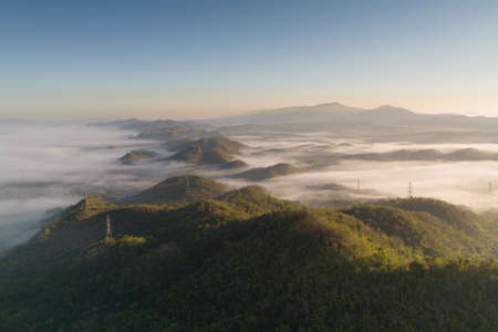 Fog in the morning forest with green mountains and high voltage pole. Pang Puai, Mae Moh, Lampang, Thailand.の写真素材