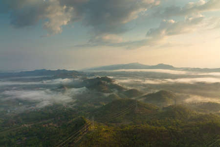 Fog in the morning forest with green mountains and high voltage pole. Pang Puay, Mae Moh, Lampang, Thailand.の写真素材