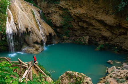 Tourists in red shirts backpacker take a photo and admiring the beauty of Koh Luang Waterfall, Lamphun, Thailand.の写真素材