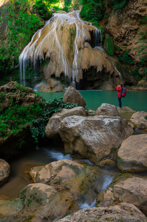 Tourists in red shirts backpacker take a photo and admiring the beauty of Koh Luang Waterfall, Lamphun, Thailand.の写真素材