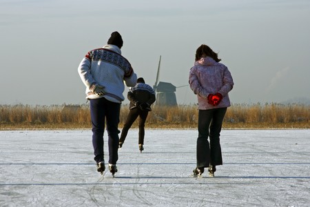 Ice skating on a cold winterday in the countryside on a frozen lake in the Netherlands  の写真素材