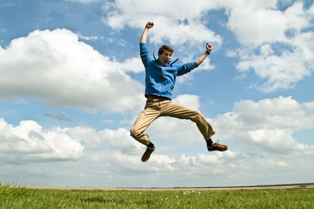 Happy guy jumping in the air on a beautiful day in springtimeの写真素材