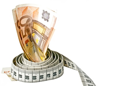 Money with a tape measure wrapped around it over a white backgroundの写真素材