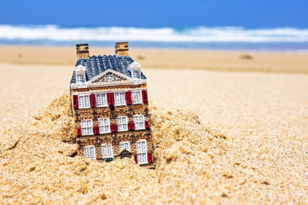 House disappearing in the sand. Concept for real estate in crisis timeの写真素材