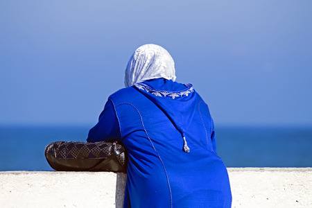 Arab woman with Islamic headscarf looking over the oceanの写真素材